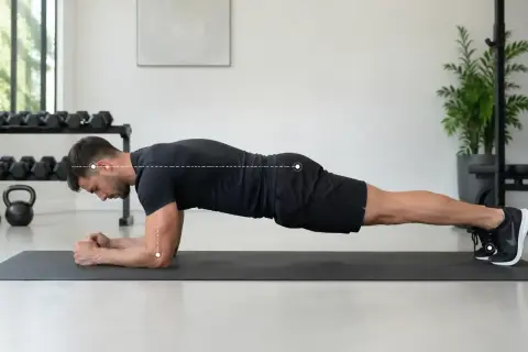 Un homme effectue un gainage planche sur un tapis de gym, le corps droit, soutenu par ses avant-bras et ses pieds.