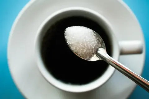 Cuillère de sucre au-dessus d'une tasse de café noir. Une image pour illustrer l'arrêter le sucre effet.