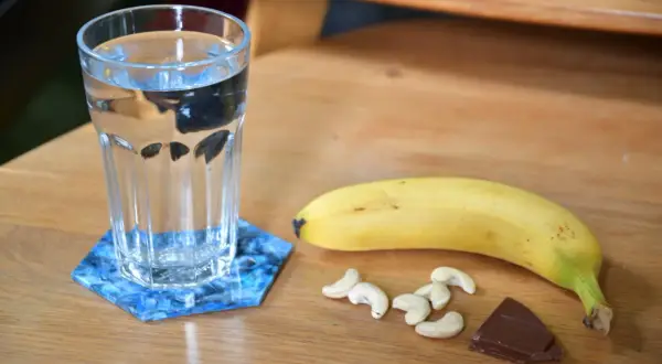 Verre d'eau, banane, noix de cajou et chocolat : idéal pour savoir quoi manger avant de courir le matin.