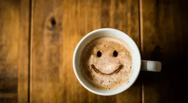 Tasse de café avec un visage souriant, une boisson qui ne fait pas grossir si consommée avec modération.