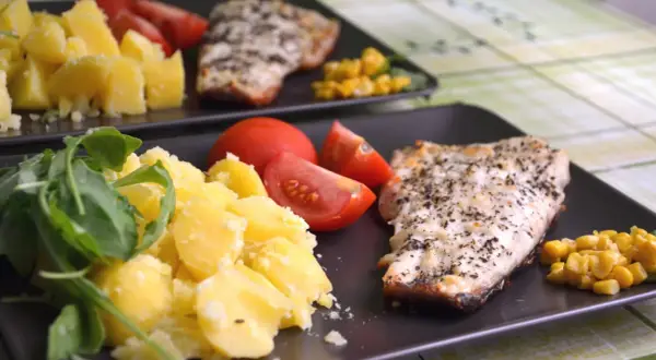 Deux assiettes de poisson grillé avec pommes de terre, tomates et maïs. Un repas sans sucre, sain et savoureux.