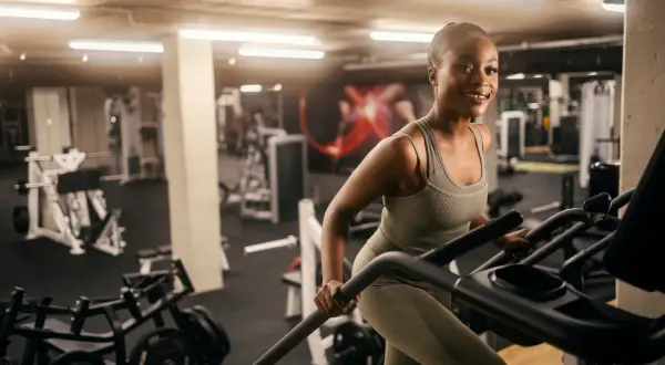 Femme souriante sur un tapis roulant, un excellent exercice pour perdre du ventre rapidement.