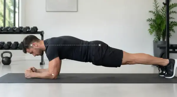 Un homme effectue un gainage planche sur un tapis de gym, le corps droit, soutenu par ses avant-bras et ses pieds.