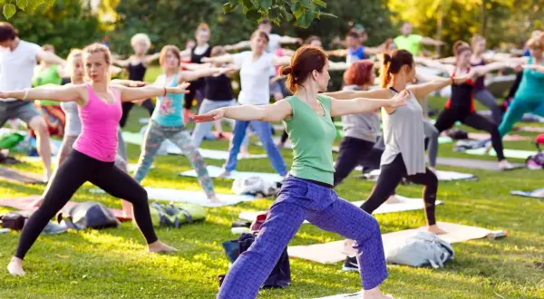 Un groupe de personnes pratique le yoga en plein air, profitant du soleil. Faire du yoga tous les jours apporte calme et équilibre.